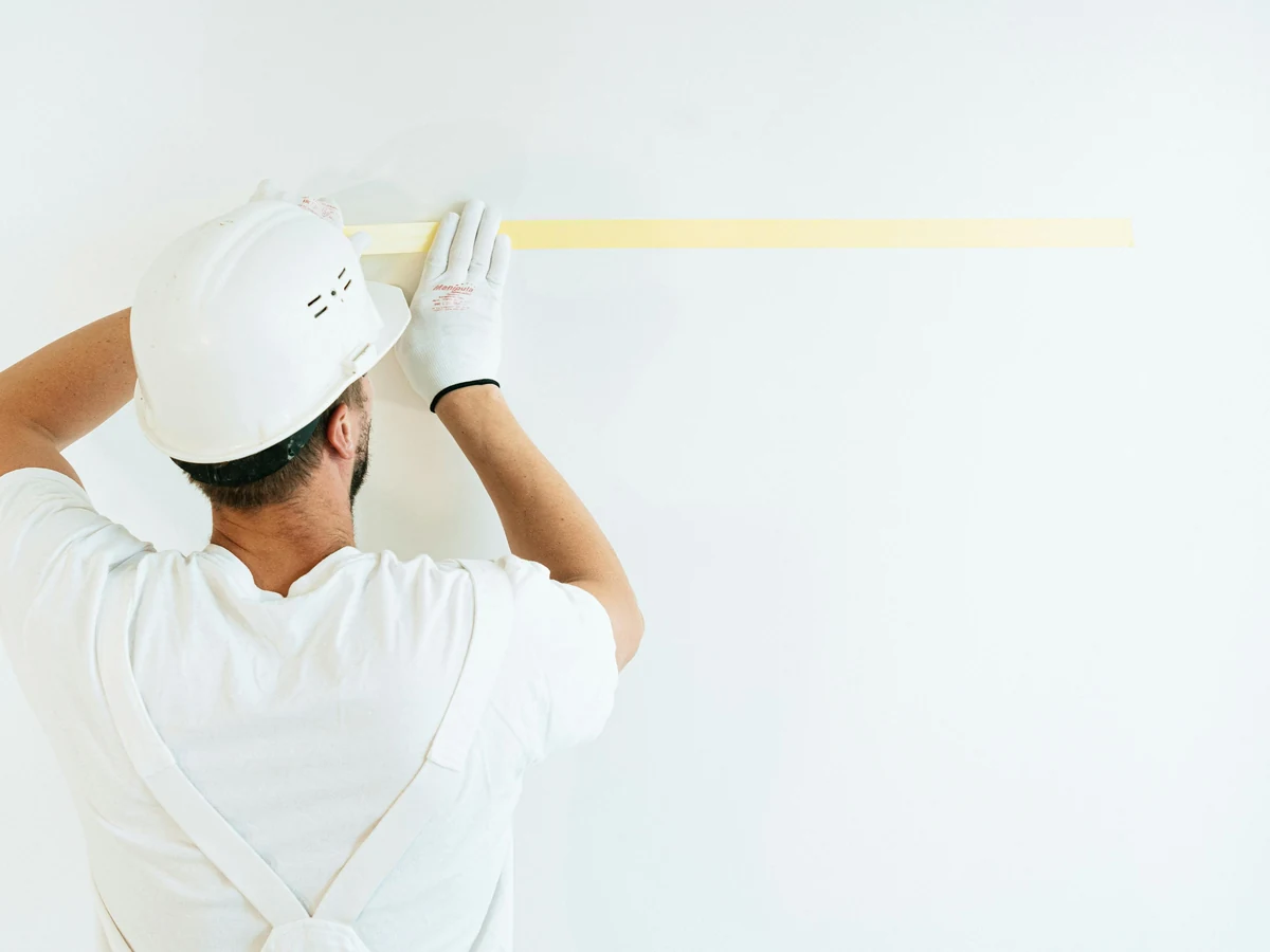 Professional decorator sanding ceiling plasterboard preparation in Wilmslow