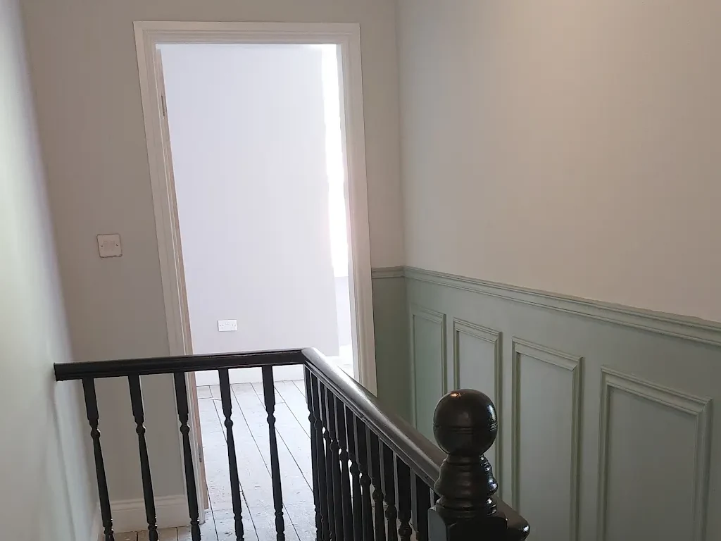 Period staircase landing with painted wall panelling and a dark bannister by Cheshire Painters.
